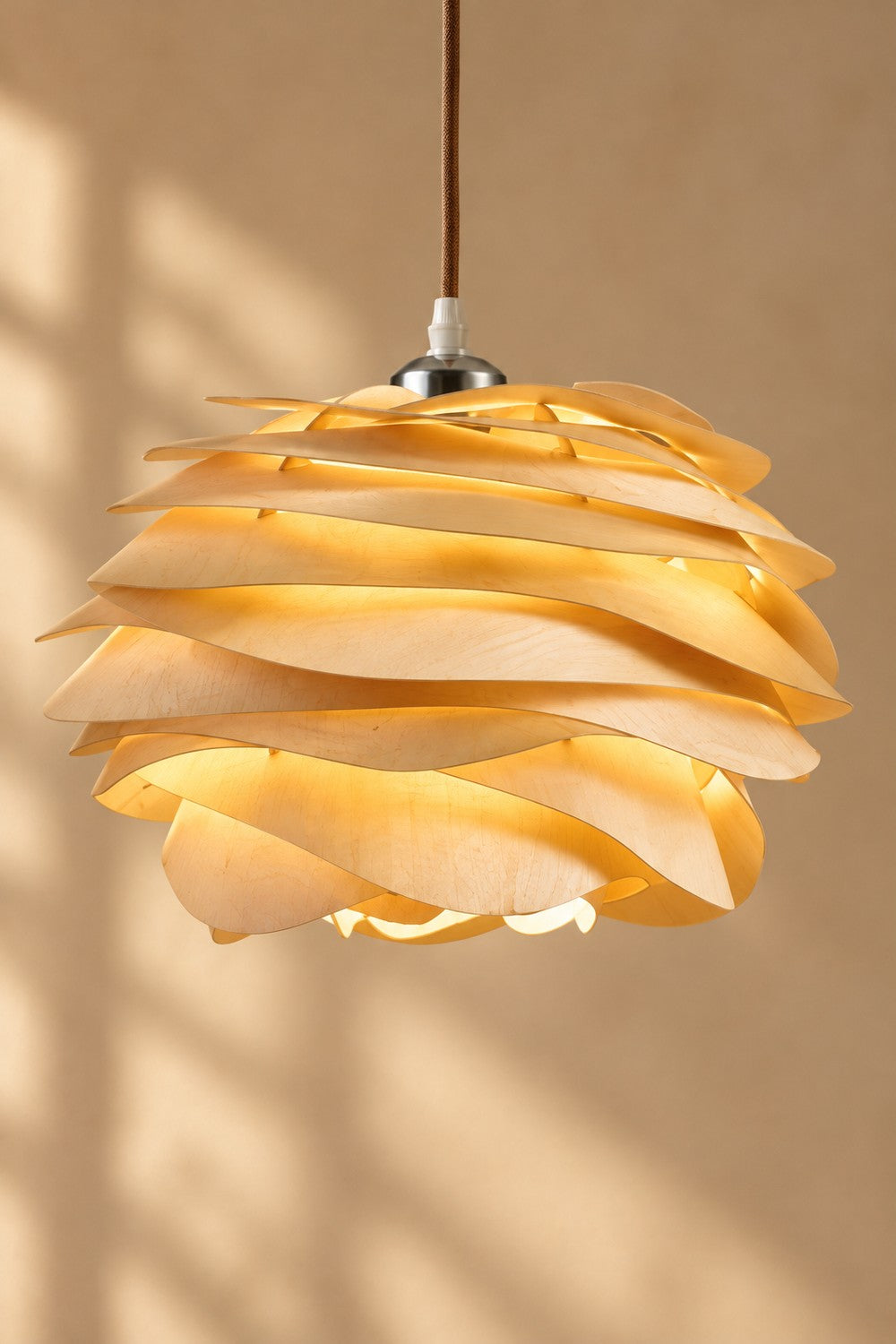 Suspension KOGLE allumée, lumière dorée entre les lamelles